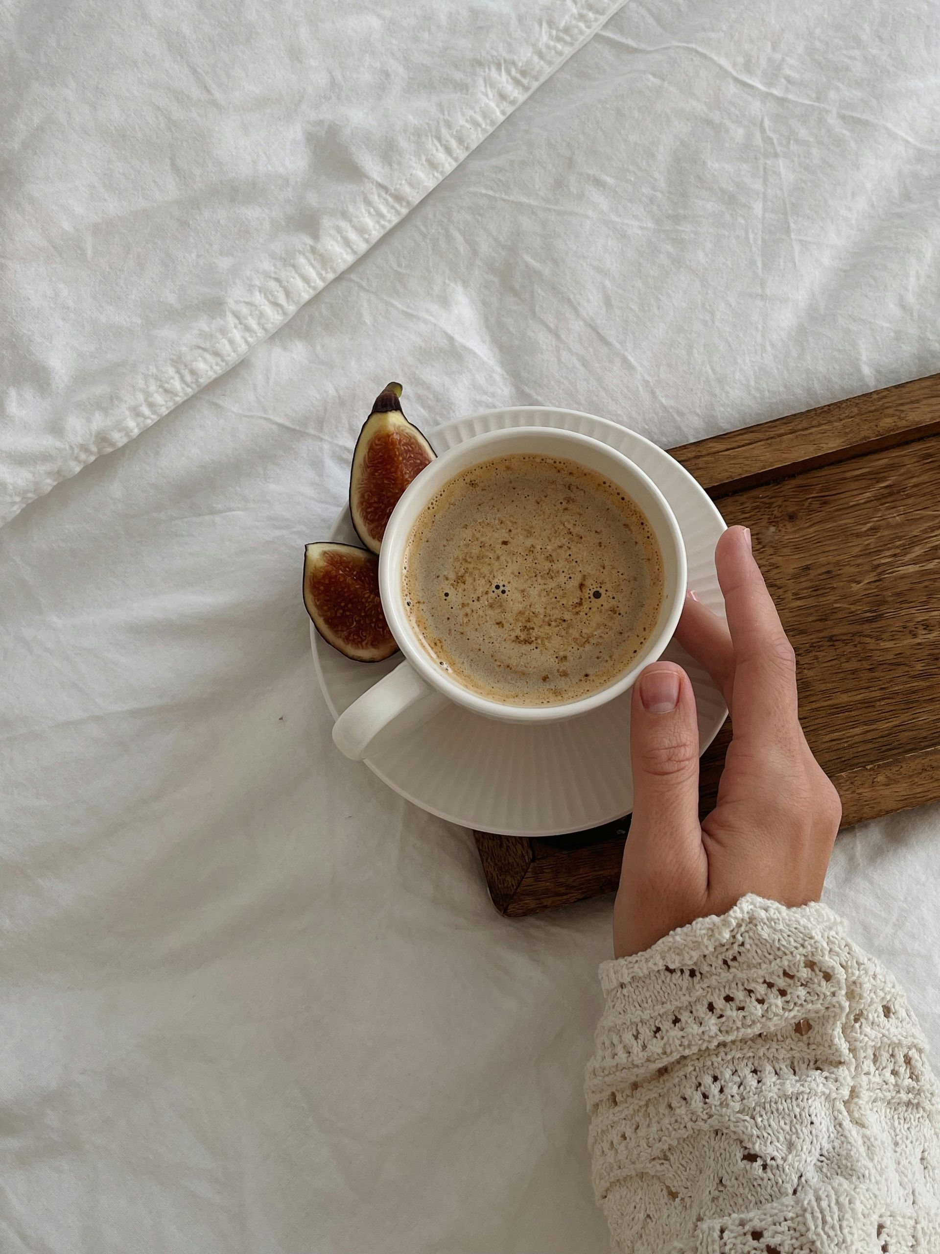 A person is holding a cup of coffee on a saucer.