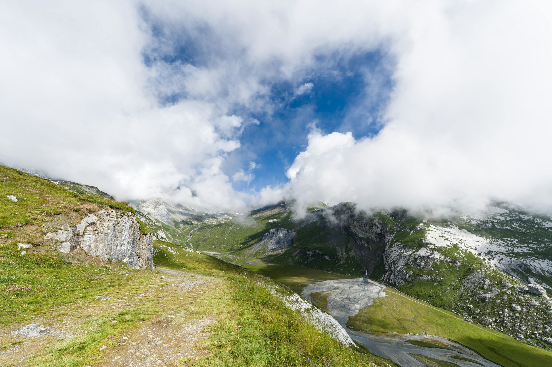 A dirt road in the mountains with clouds in the sky