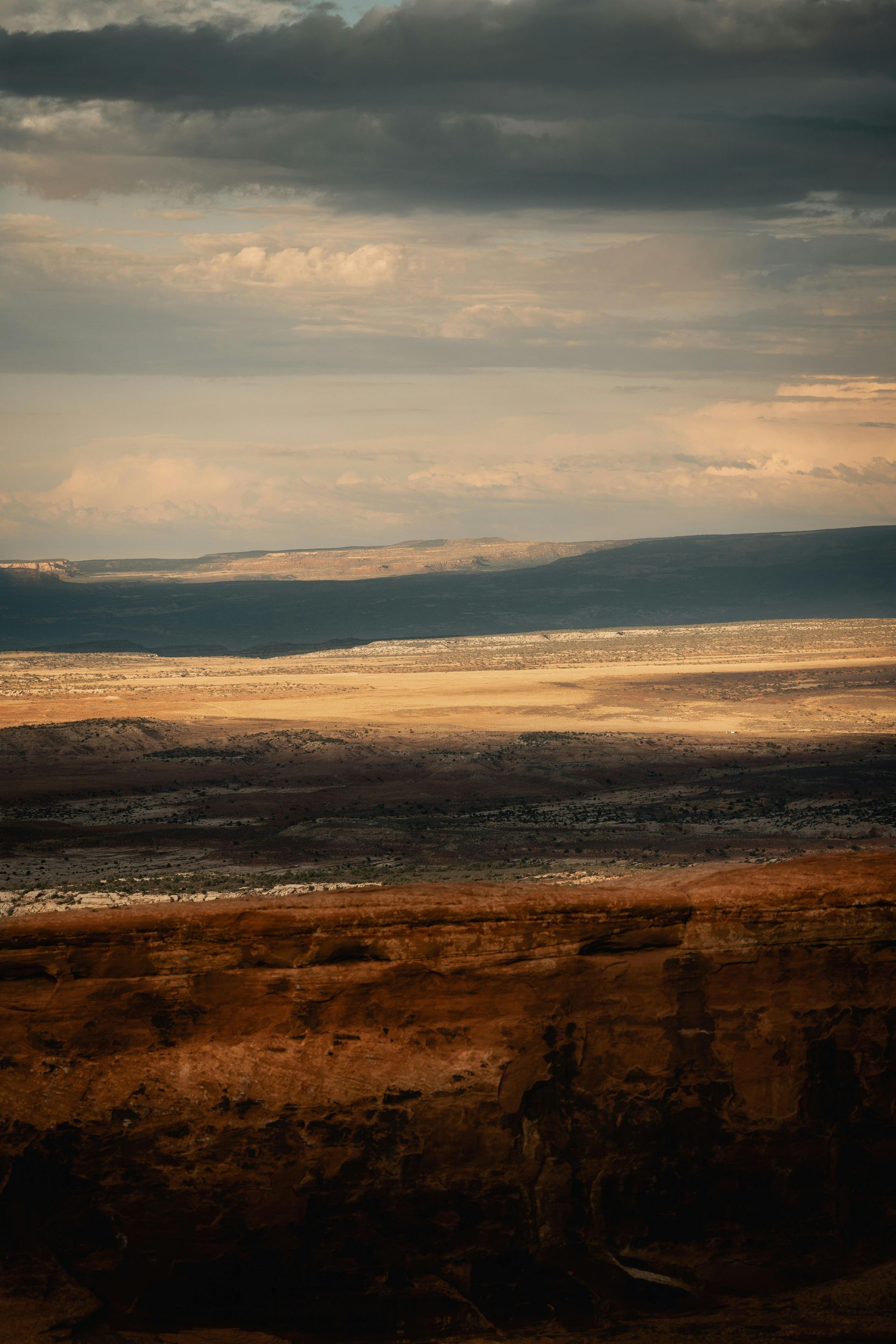 A desert landscape with mountains in the background and a cloudy sky