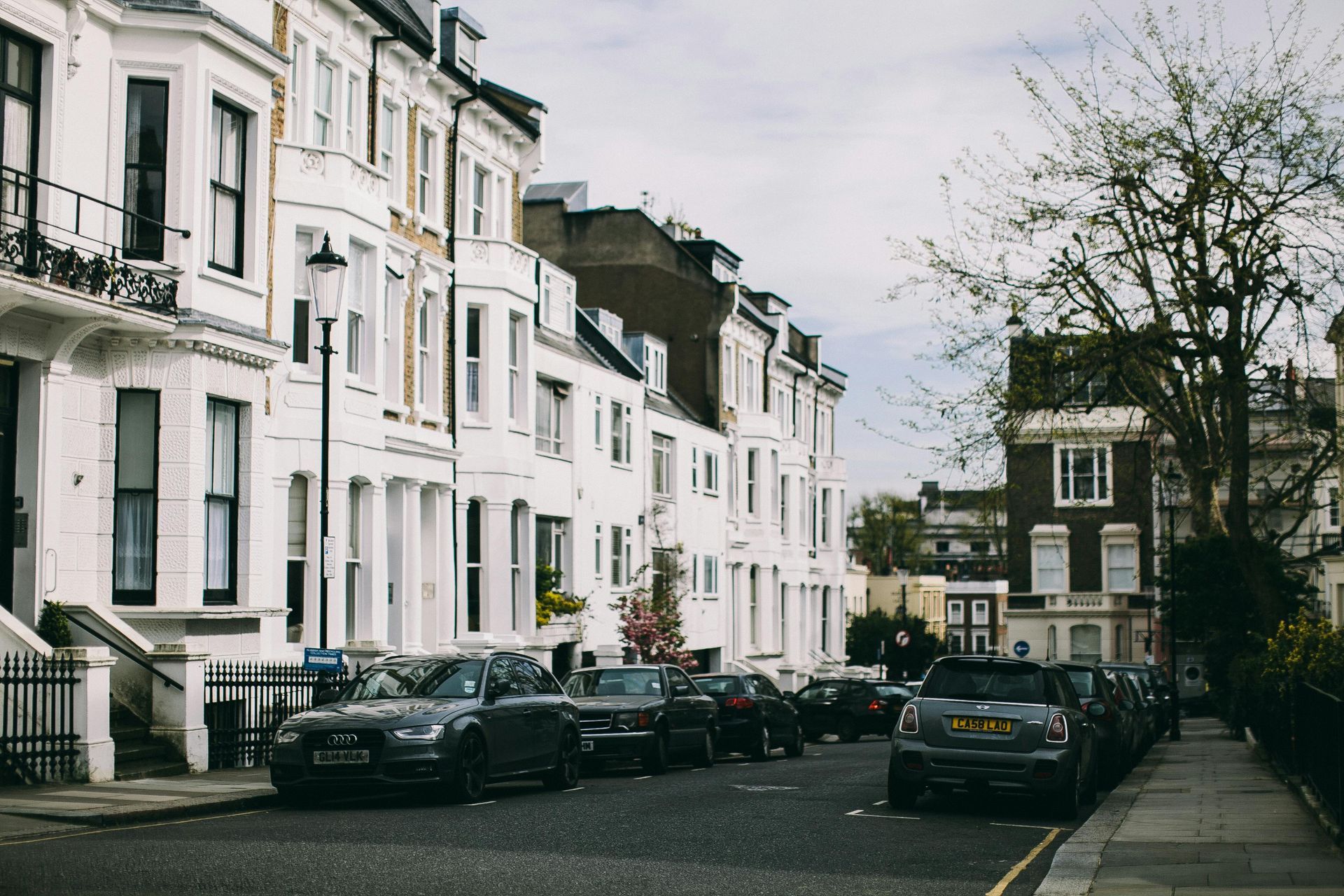 A row of houses with cars parked on the side of the road.