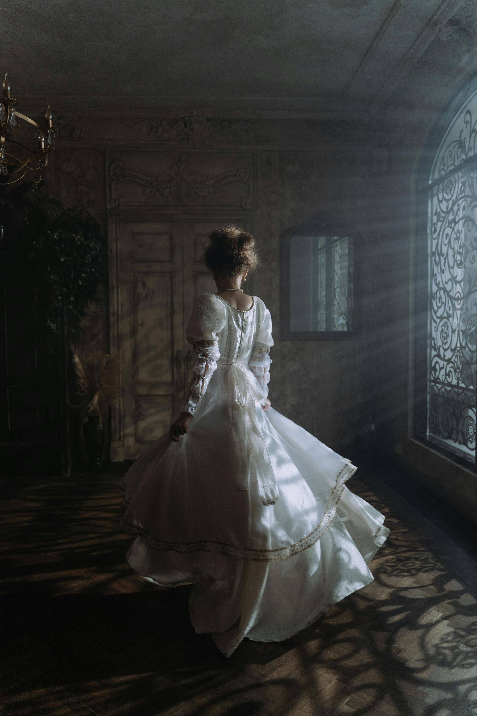 A woman in a white dress is dancing in a dark room.