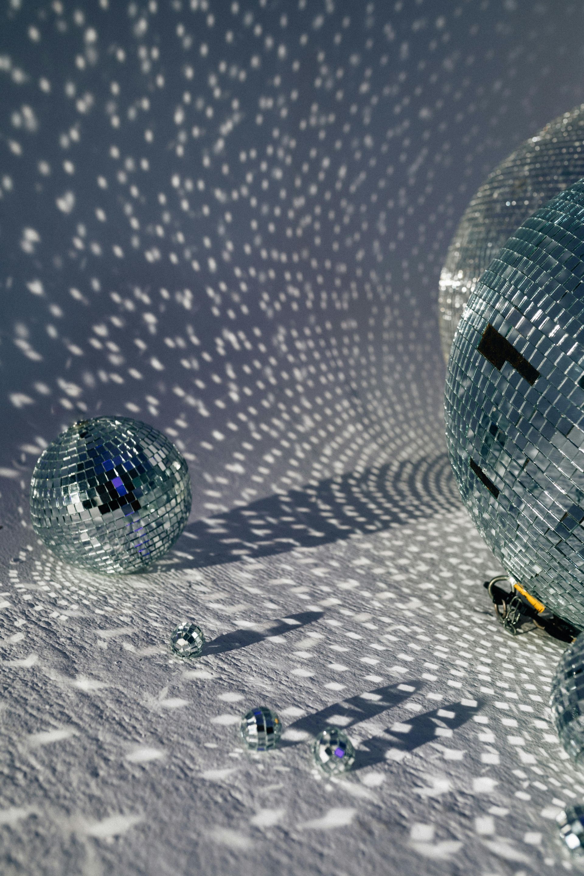 Two disco balls are sitting on a white surface.