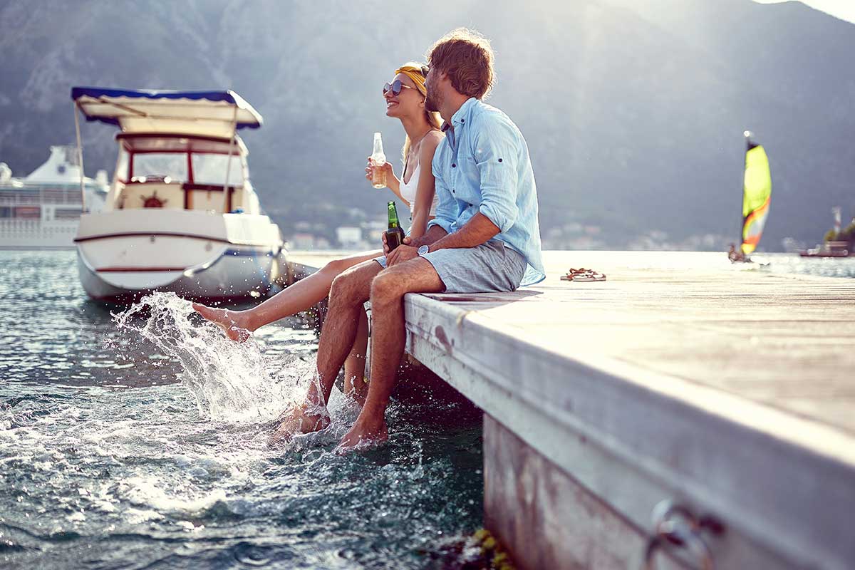 A man and a woman are sitting on a dock near the water.
