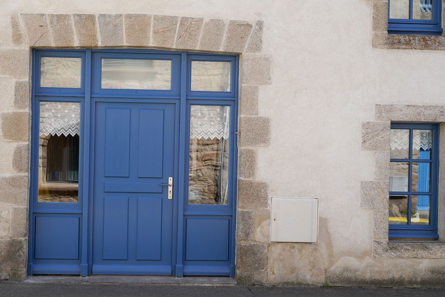Une porte d'entrée bleue avec des vitres sur les côtés, les fenêtres sont assorties