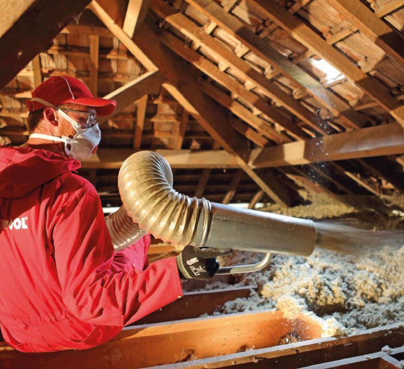Un homme isole des combles perdus en propulsant de la laine de roche Rockwood