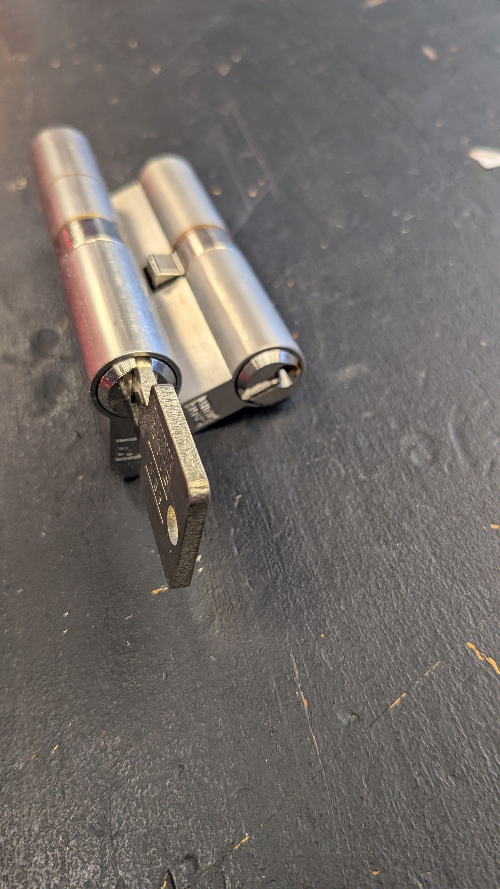 Clé insérée dans un cylindre de serrure de porte argenté sur une surface sombre.