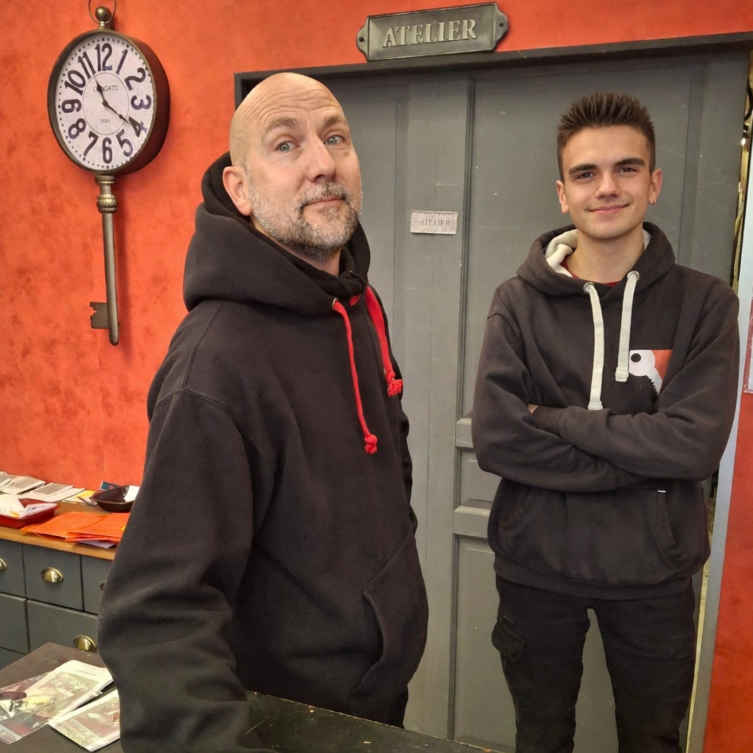 Personnel d’atelier en sweat noir devant une porte signalée Atelier