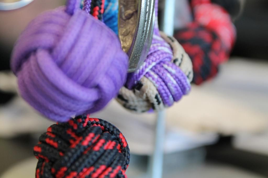 Gros plan sur des jouets en corde colorée et nouée, suspendus à un anneau argenté.