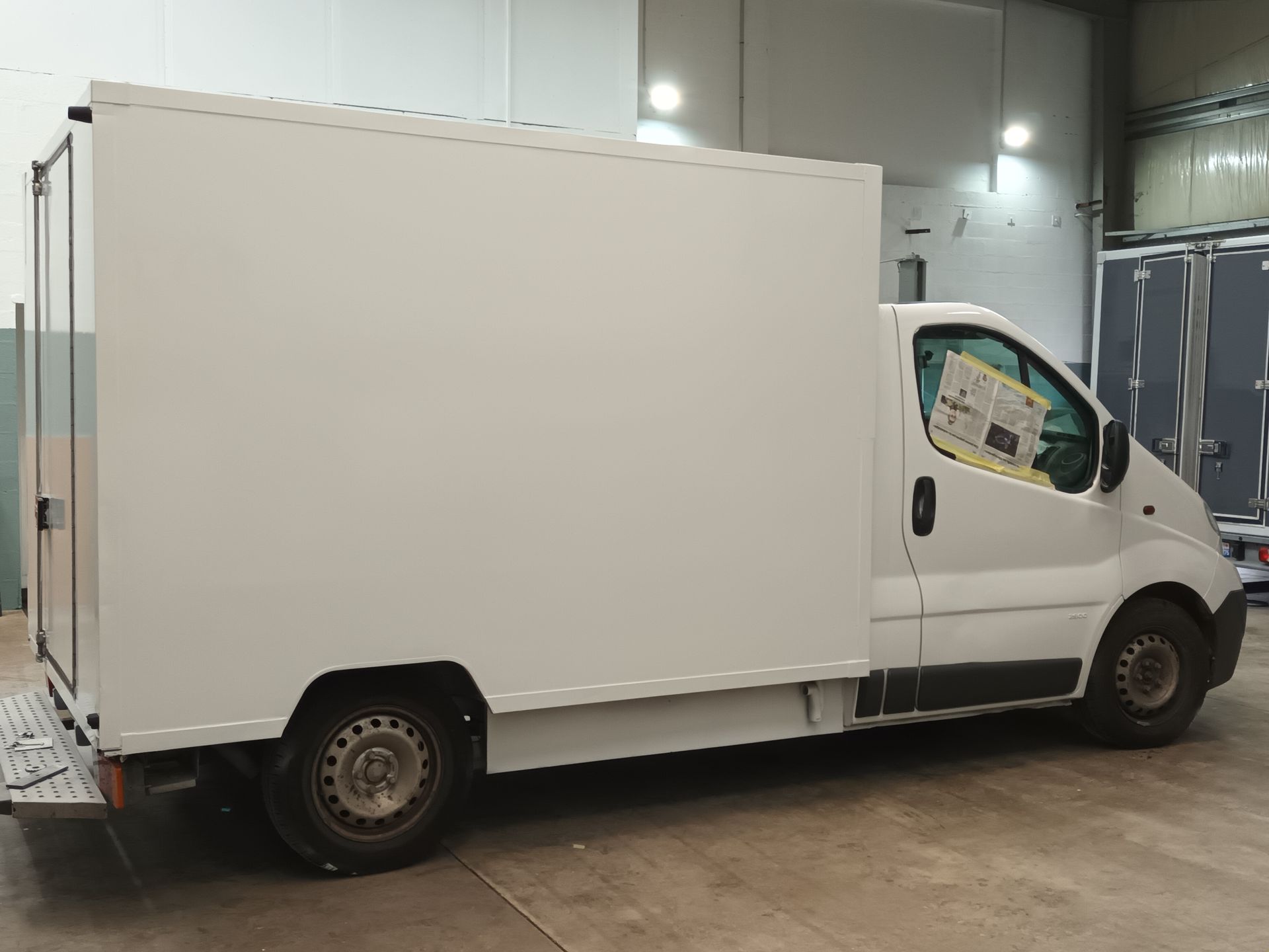 Un camion blanc vu de profil garé dans un garage couvert