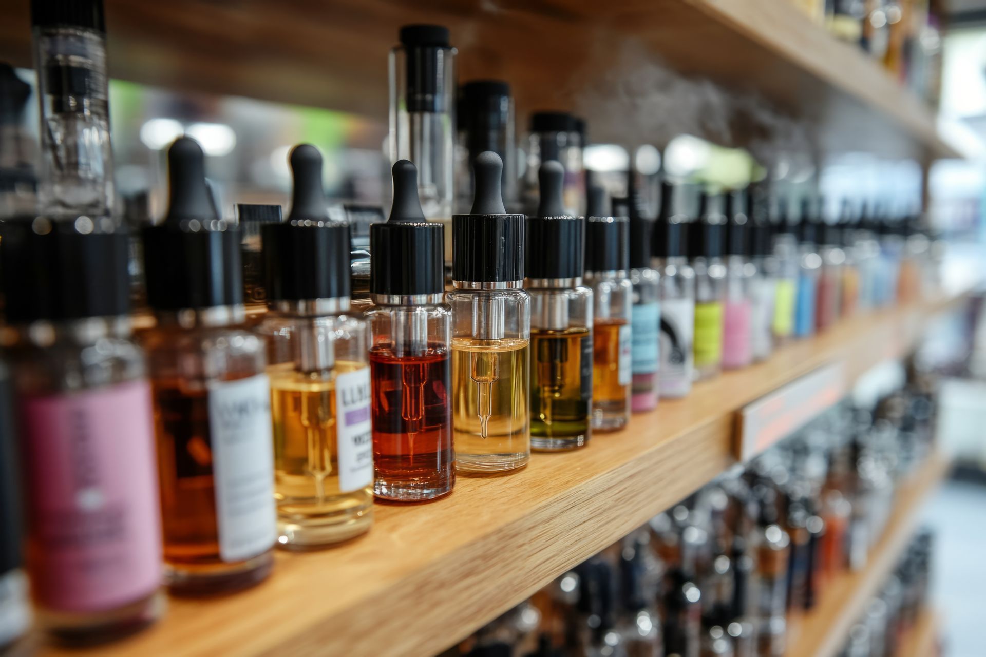 Une personne remplit un stylo vape avec du e-liquide rouge provenant d'une bouteille, posée sur une table en bois. Une bouteille d'e-liquide bleu est également présente.