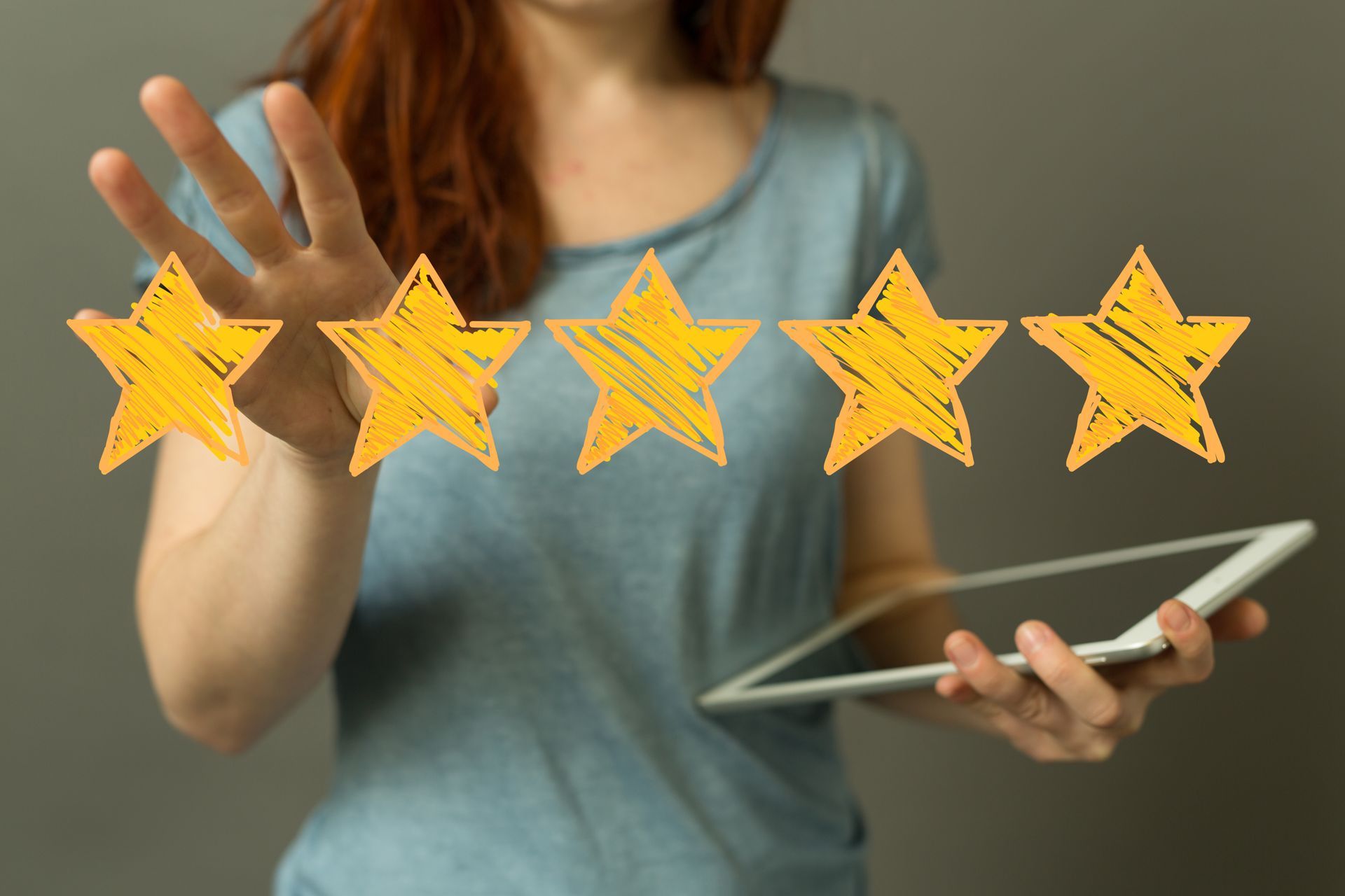 Une femme tenant une tablette, tendant la main vers cinq étoiles dorées, symbolisant une note de 5 étoiles.