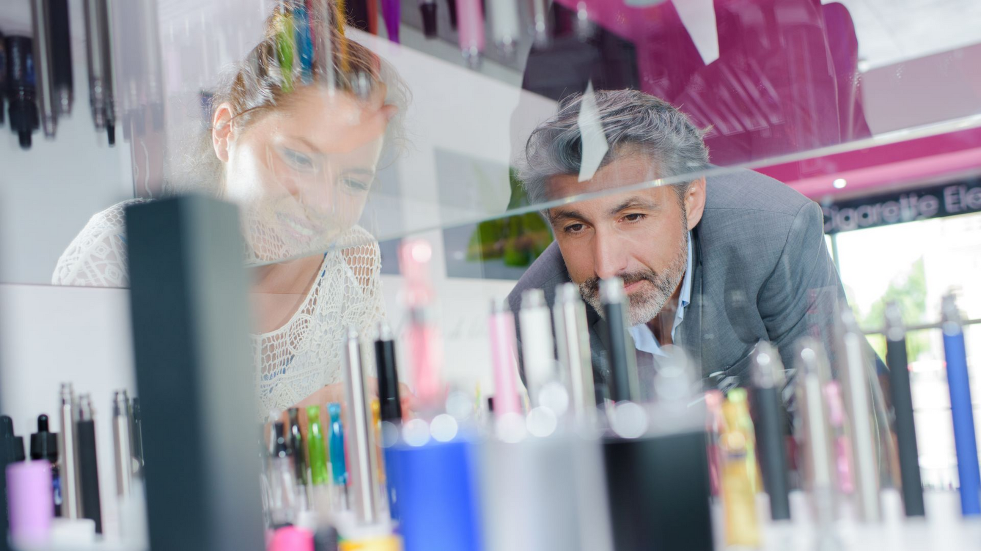 Quatre appareils de vapotage différents sur une surface blanche : deux complets, un réservoir et une bouteille.