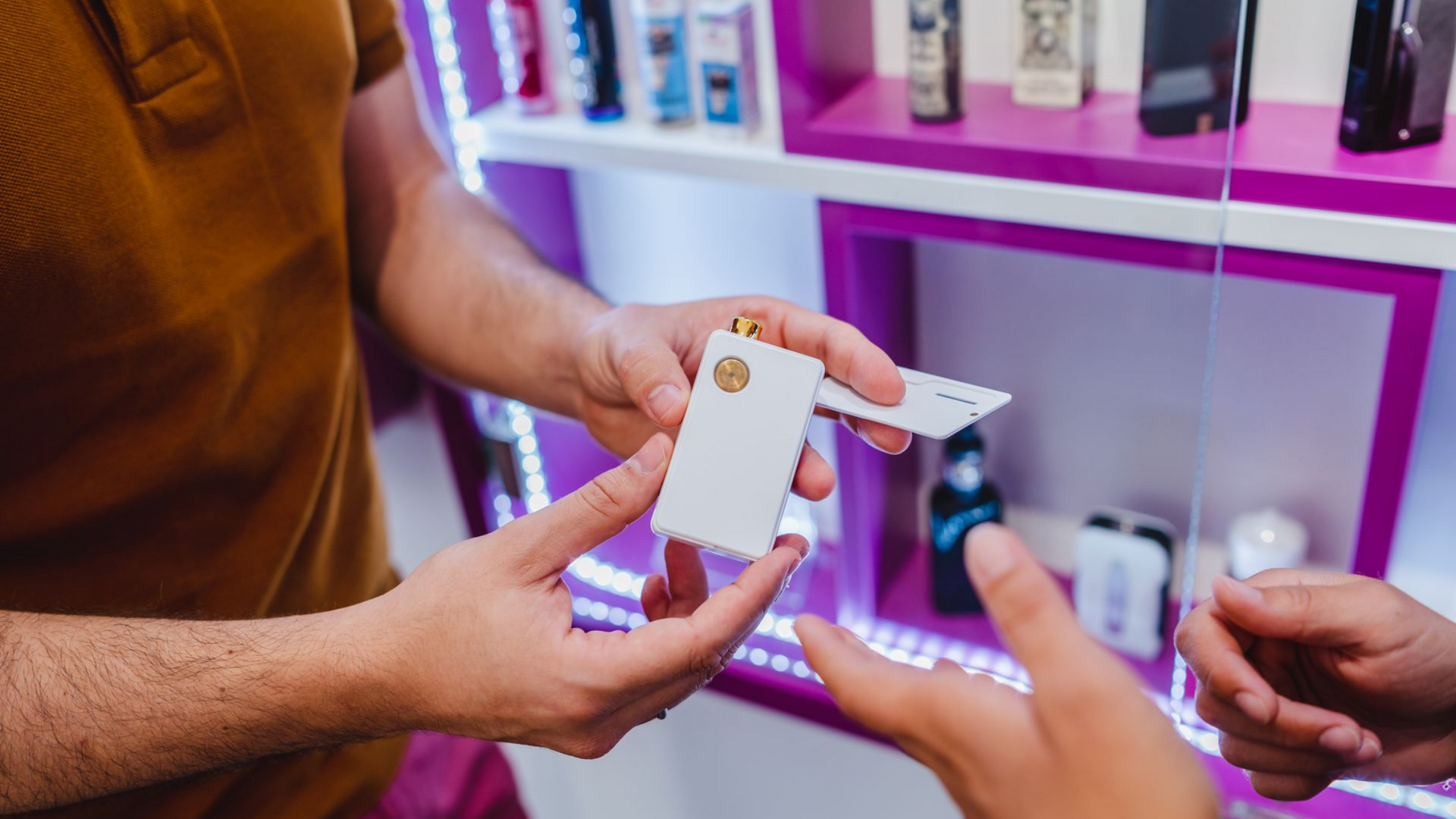 Une personne montrant un appareil de vapotage blanc à une autre personne dans un magasin de vapotage.