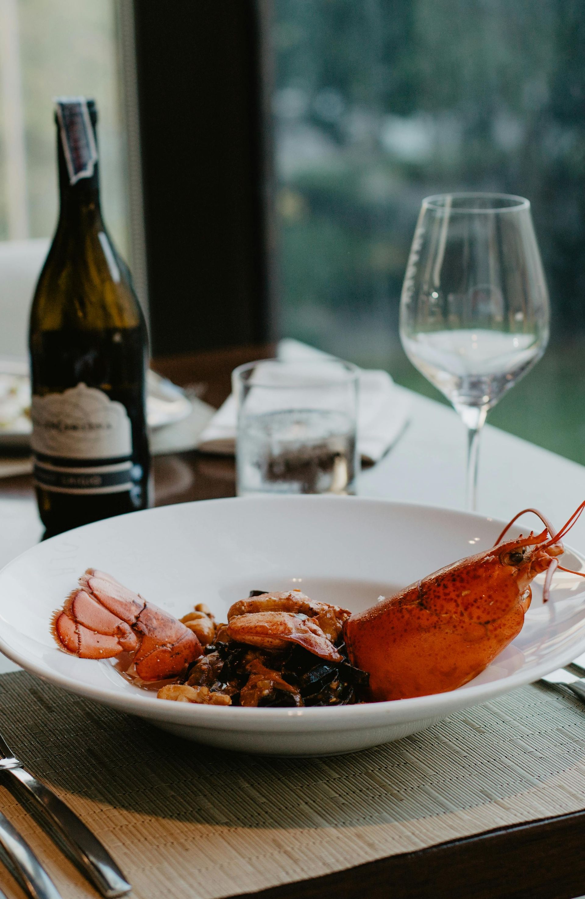 Plat de homard sur une table blanche avec une bouteille de vin 