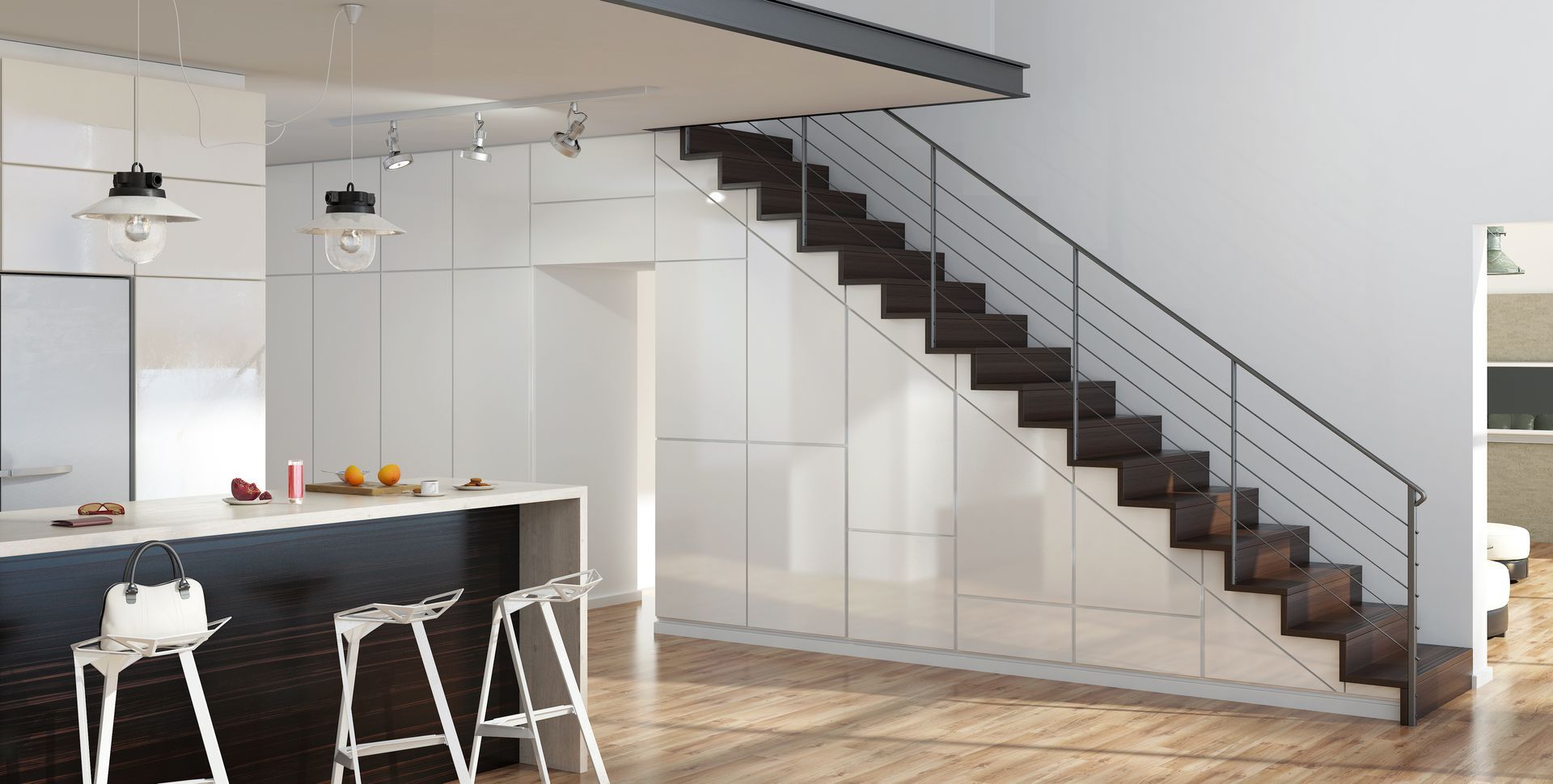 Une cuisine moderne avec un comptoir de bar foncé, des placards blancs et un escalier ouvert aux marches foncées sur un mur blanc.