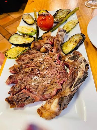 Un plato blanco cubierto con carne y verduras sobre una mesa de madera.