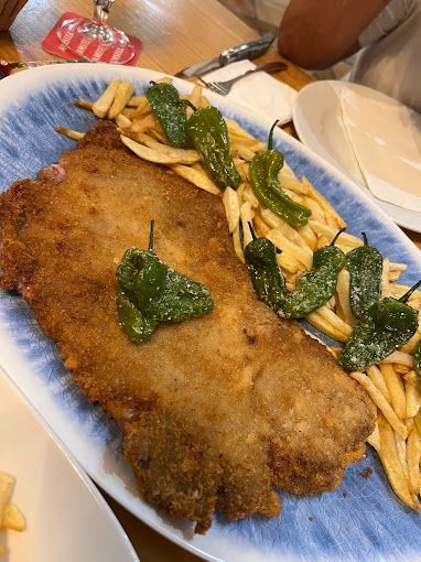 Un plato de comida con patatas fritas y pimientos verdes sobre una mesa.