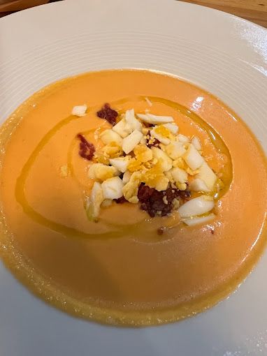 Un primer plano de un tazón de sopa con huevos y aceite de oliva sobre una mesa.