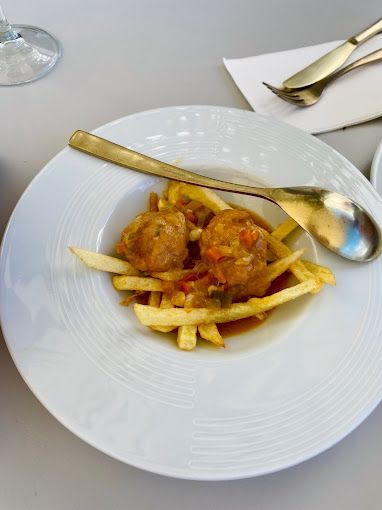 Un plato de comida con albóndigas y patatas fritas en una mesa.