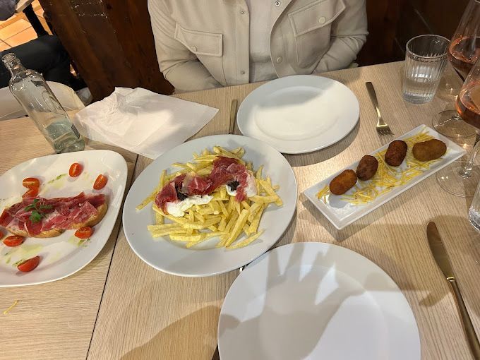 Una mujer está sentada en una mesa con platos de comida sobre ella.