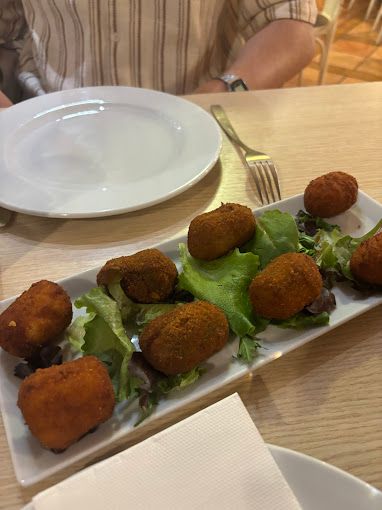 Un plato blanco cubierto con comida frita y lechuga sobre una mesa.