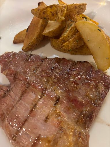 Un primer plano de un filete y patatas gajo en un plato.