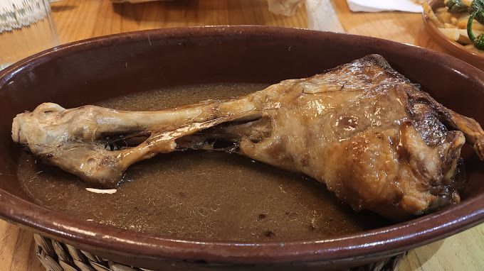 Un trozo de carne está sentado en un recipiente con salsa sobre una mesa.