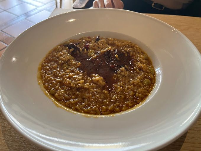 Un plato blanco cubierto con arroz y salsa sobre una mesa de madera.