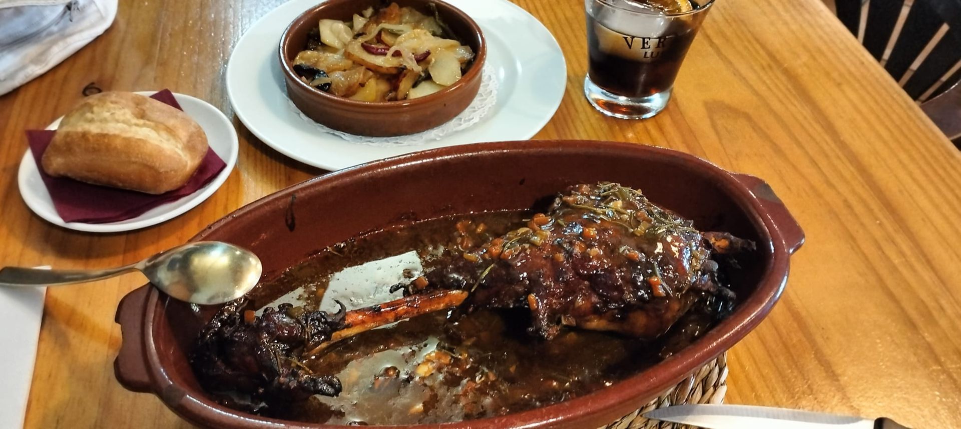 Una cazuela llena de carne y salsa sobre una mesa de madera.