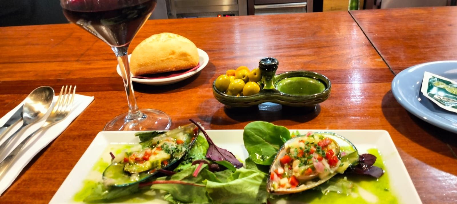 Un plato de comida y una copa de vino en una mesa de madera.