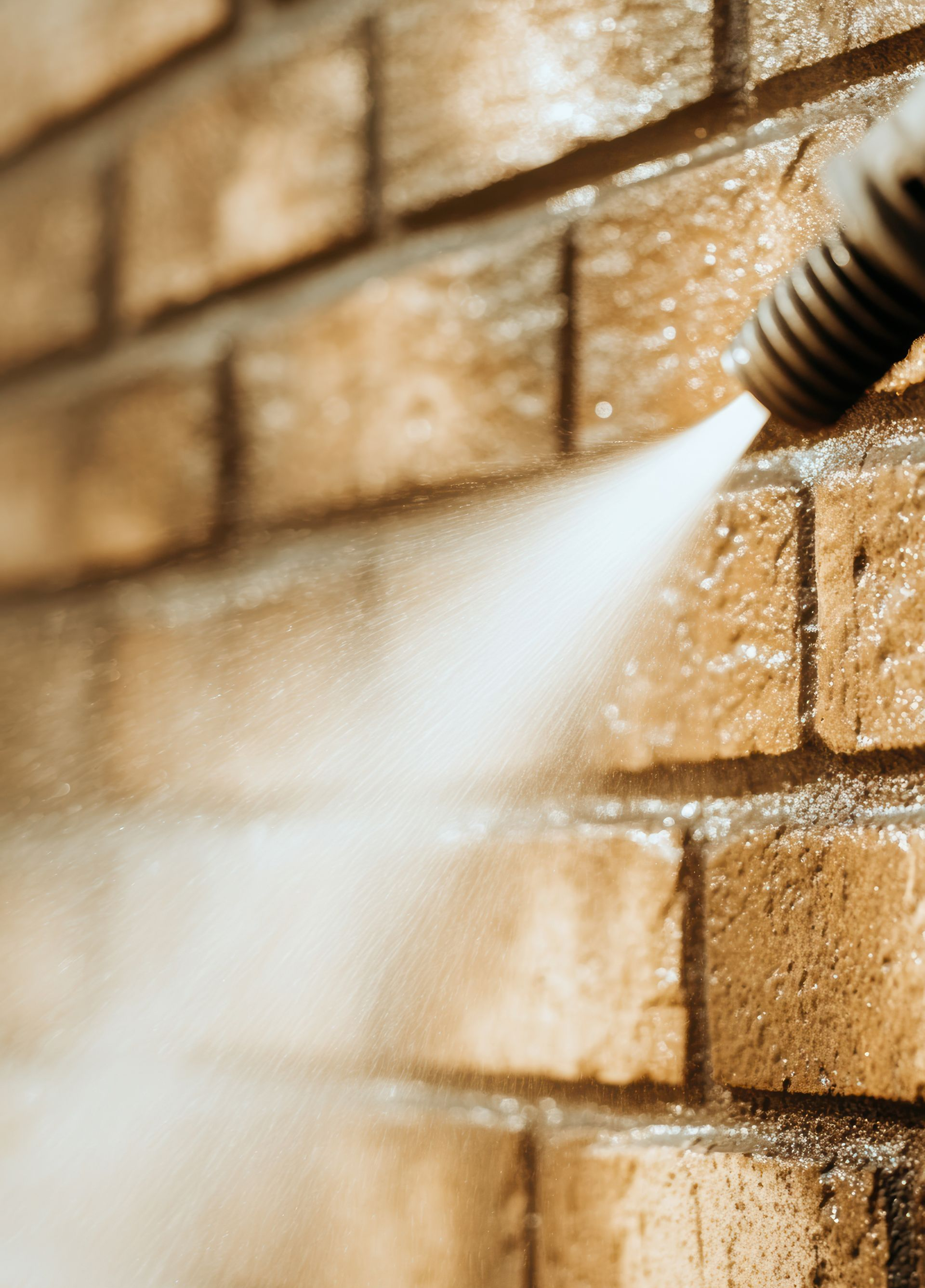 Un jet d'eau à haute pression pulvérise un mur de briques, nettoyant la surface.