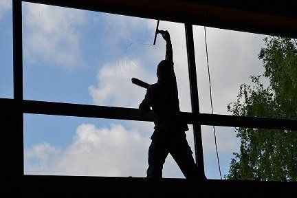 Un agent d'entretien à contre jour qui lave des vitres 