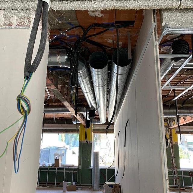 Un edificio en construcción con tuberías y cables colgando del techo.