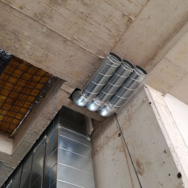 Un montón de tubos de metal cuelgan del techo de un edificio.