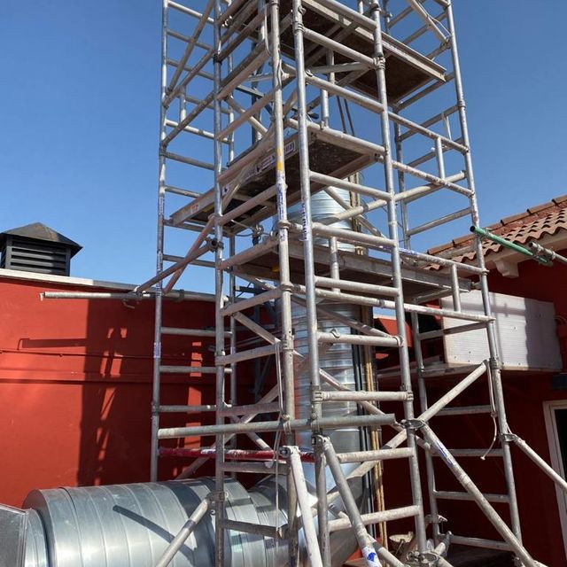 Una torre de andamios está delante de un edificio rojo.