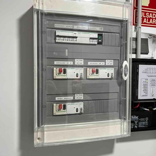 Una gran caja eléctrica está colgada en una pared junto a un cartel que dice Alarma Ulsad.
