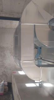 Un conducto de acero inoxidable cuelga del techo de un edificio.