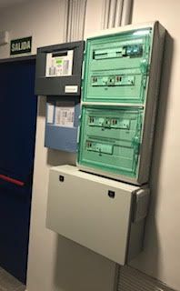 Una fila de cajas eléctricas están apiladas una encima de otra en una pared.