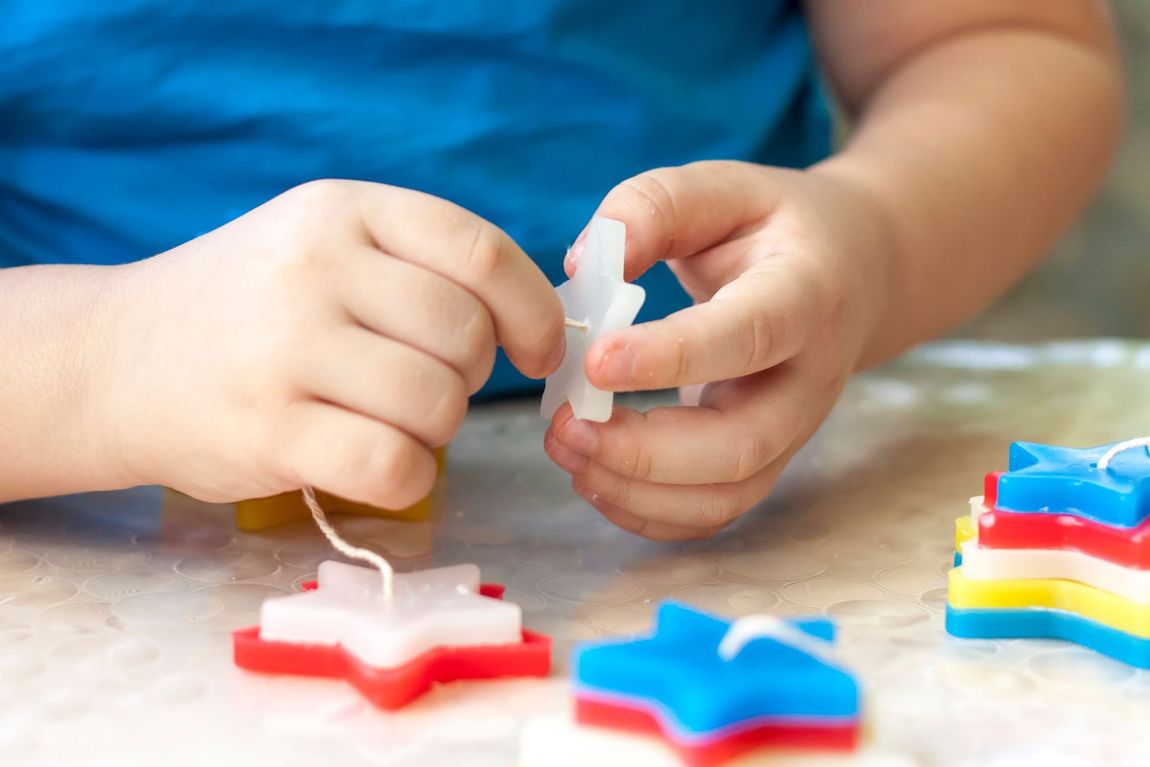 Un niño está haciendo velas en forma de estrellas.