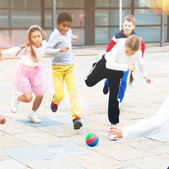 Un grupo de niños está jugando fútbol en una acera.