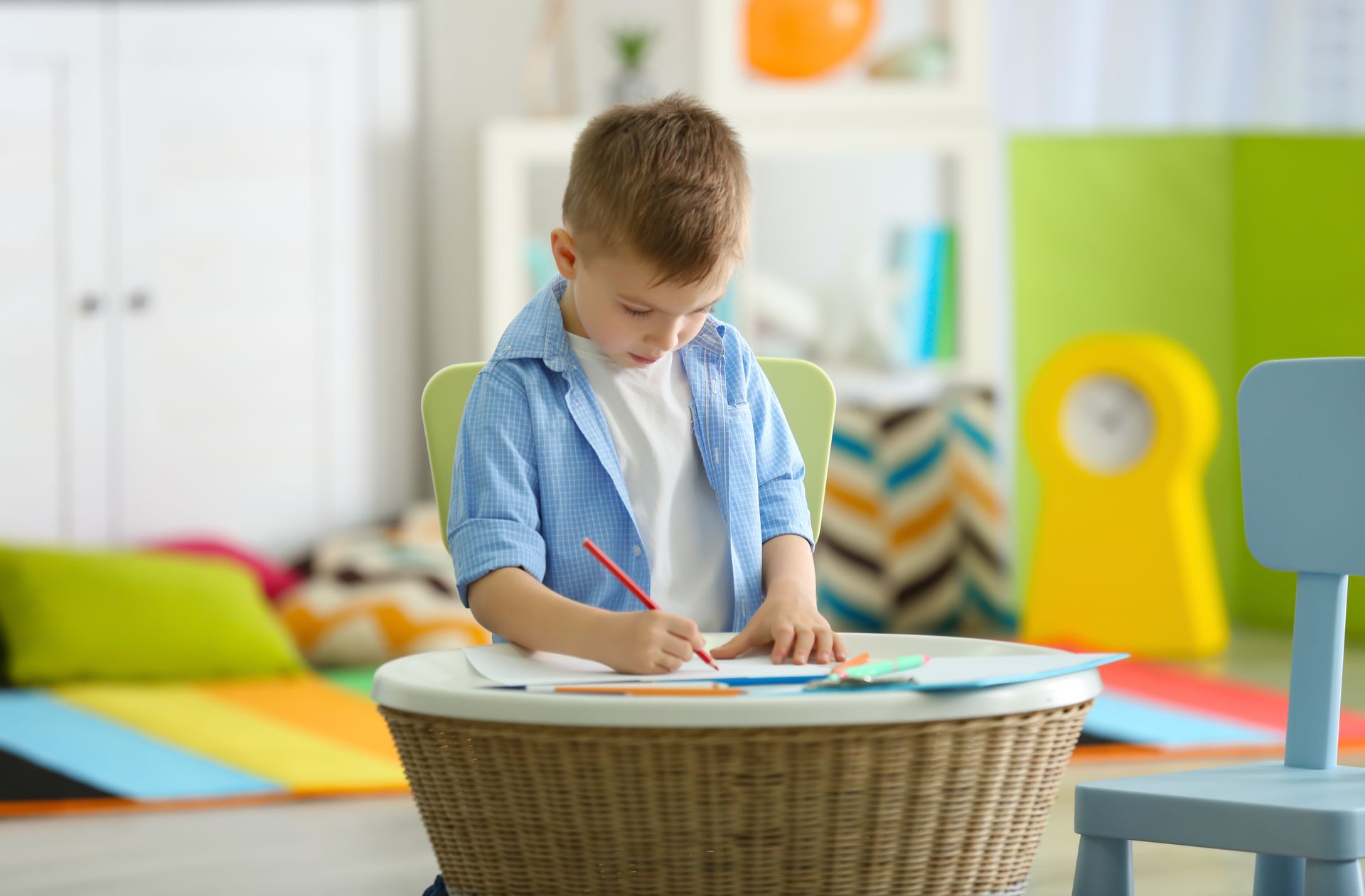 Un niño pequeño está sentado en una mesa dibujando con un lápiz.