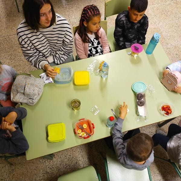 Un grupo de niños están sentados en una mesa comiendo comida.
