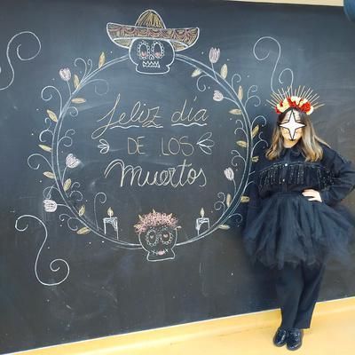 Una mujer con un vestido negro está parada frente a una pizarra.