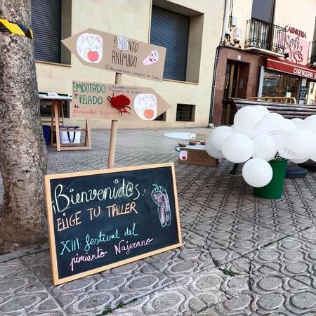 A sign on the sidewalk says bienvenidos elige tu taller