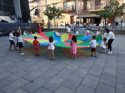 Un grupo de niños está jugando con un paracaídas colorido.
