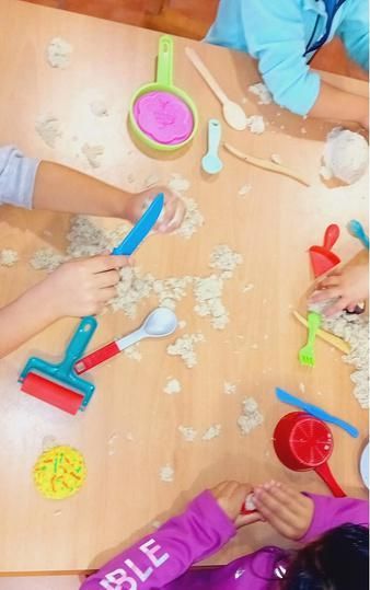 Un grupo de niños está jugando con arena cinética sobre una mesa.