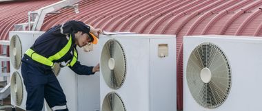 Un ouvrier inspecte les unités de climatisation sur le toit, devant les sièges du stade.