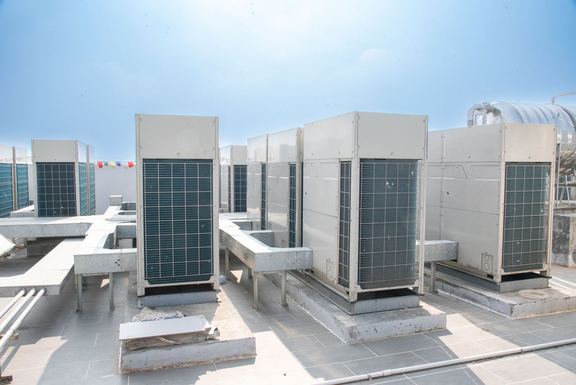 Unités de climatisation et conduits de ventilation sur le toit d'un bâtiment industriel lumineux sous un ciel bleu dégagé