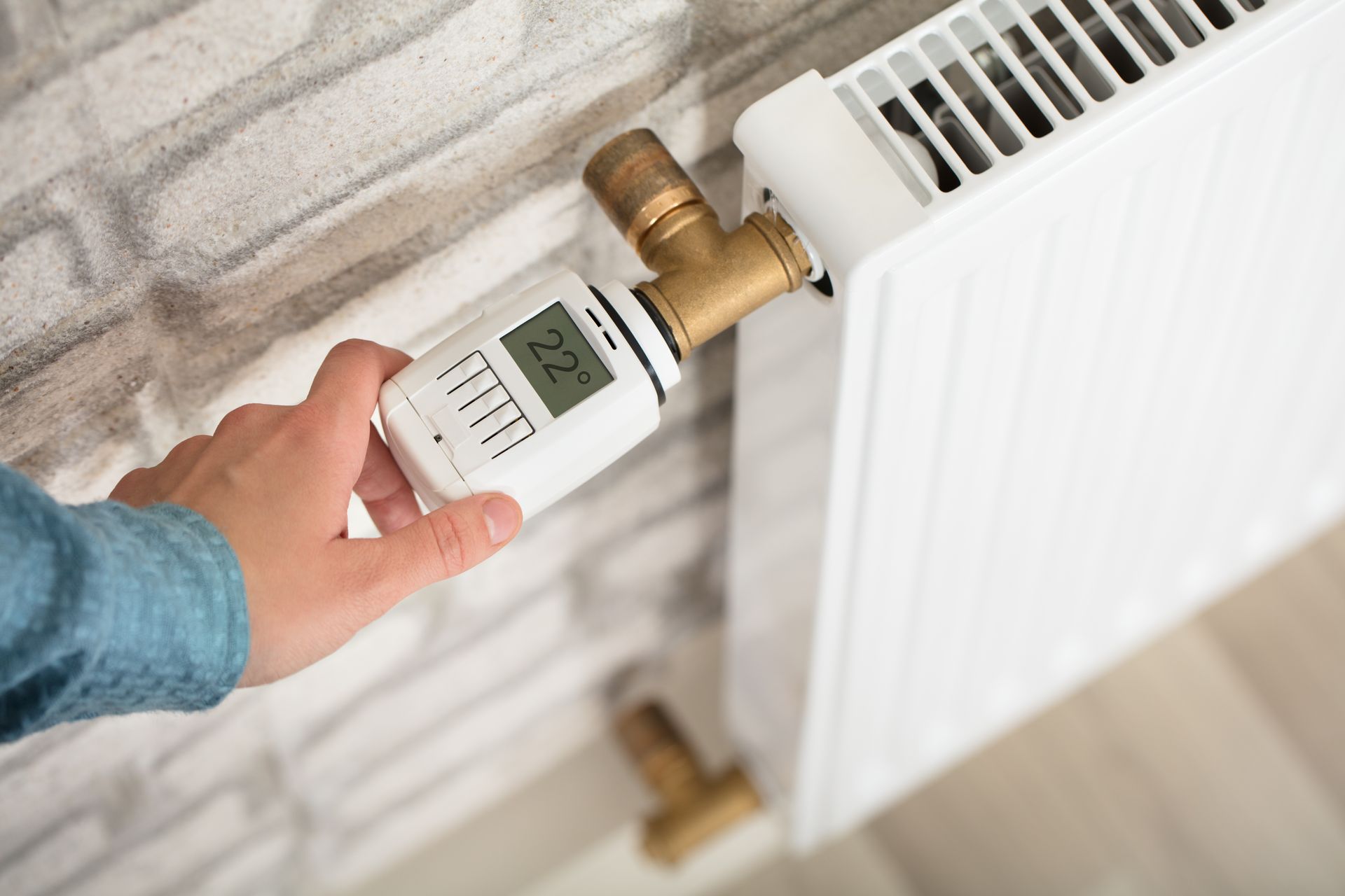 Réglage manuel d'un robinet thermostatique de radiateur sur un radiateur blanc.