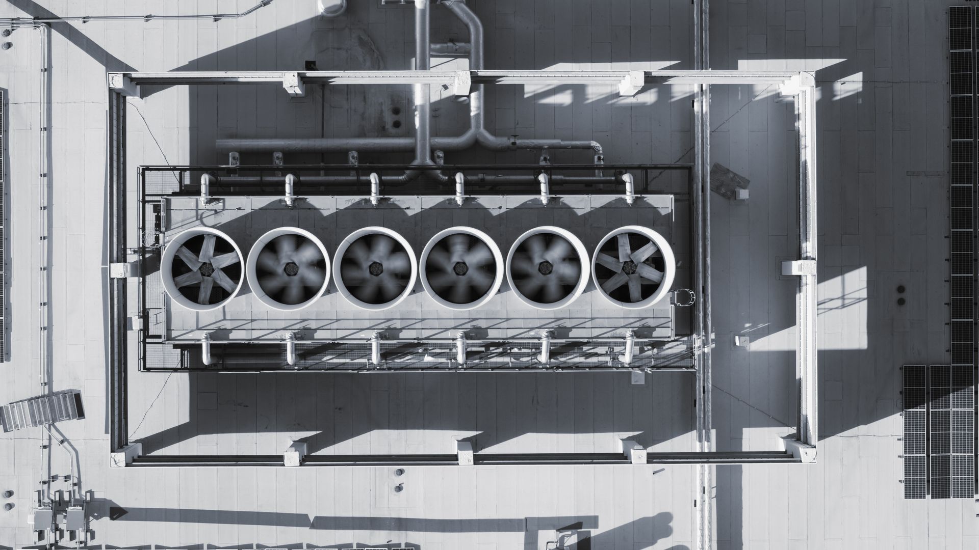 Vue aérienne d'une unité de toiture industrielle équipée de six grands ventilateurs de refroidissement.